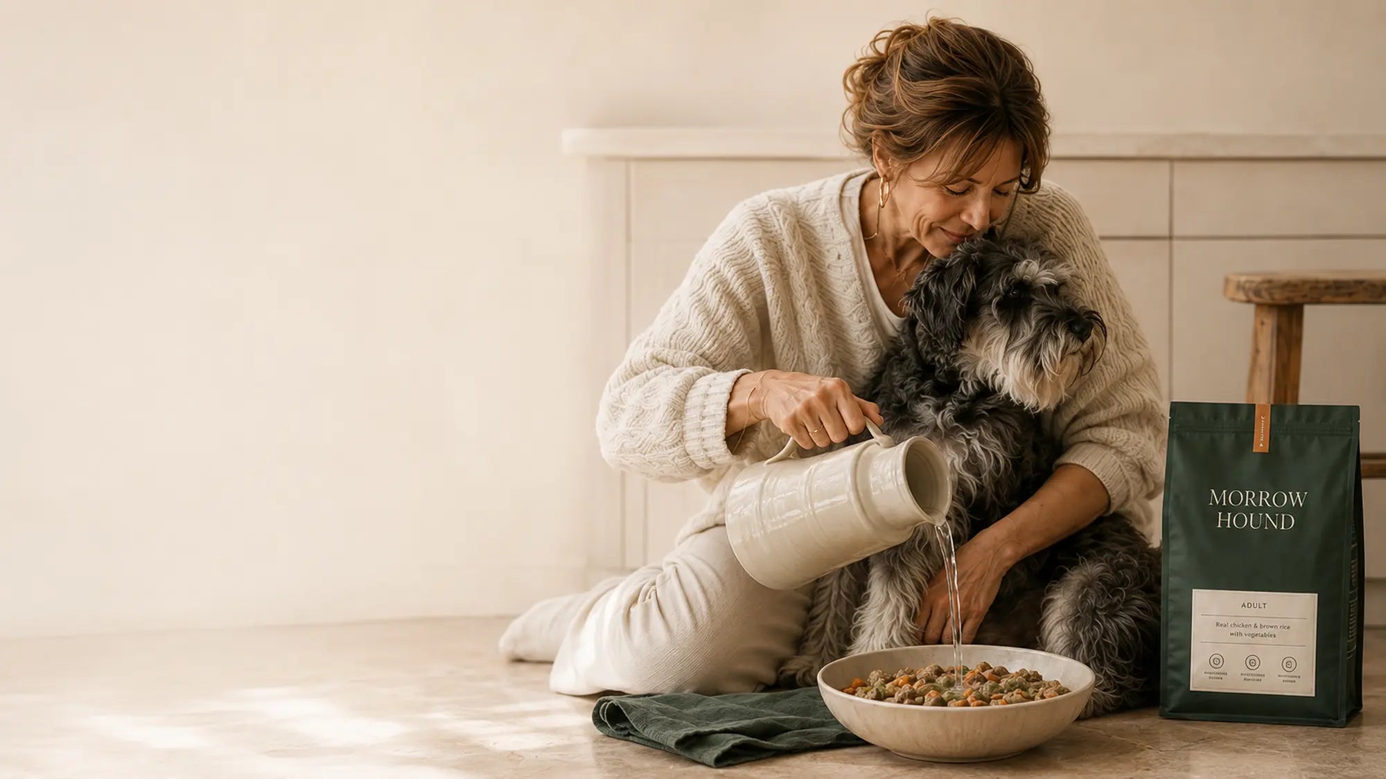 A woman adding warm water to Morrow Hound food while holding her dog close